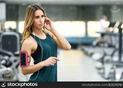 Young woman using smartphone standing in the gym before the training.