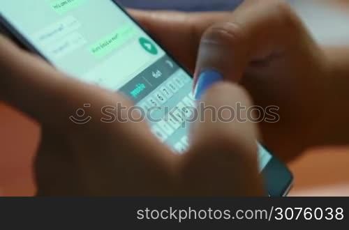Young woman using smartphone while doing homework. Hispanic people and college education. Female student studying and texting with mobile telephone at home, typing text message on cell phone. Close-up