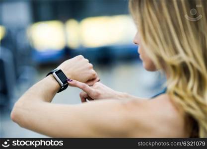 Young woman using smartwatch at the gym. Caucasian female working out.
