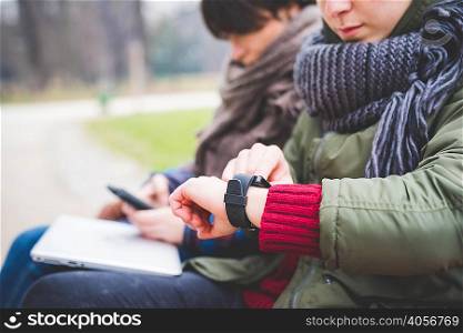 Young woman using smartwatch, outdoors