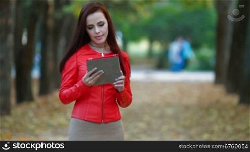 Young woman using tablet computer in autumn park