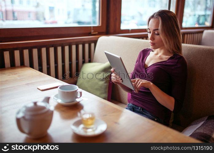 Young woman using tablet pc in cafe. Female with digital gadget using wifi in cafe.. Young woman using tablet pc in cafe.