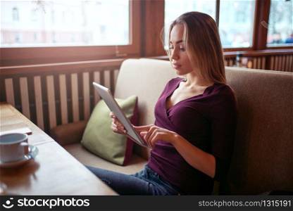 Young woman using tablet pc in cafe. Female with digital gadget using wifi in cafe.