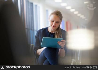 Young woman using tablet PC the waiting room of the station or airport