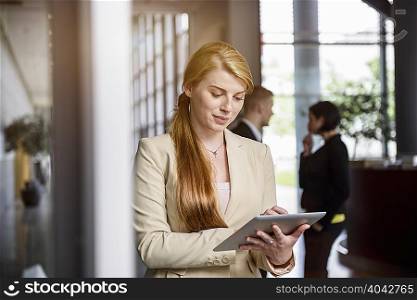 Young woman using touchscreen on digital tablet in office