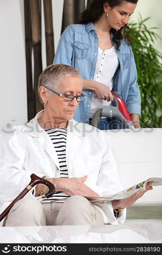 Young woman vacuuming next to senior woman