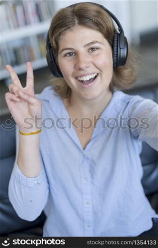 young woman victory sign at home with headphones
