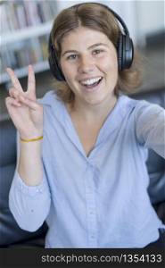 young woman victory sign at home with headphones