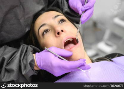 Young woman visit dentistry clinic for professional teeth treatment. Woman dentist bend over patient. Doctor holding instrument tool for oral examination. High quality photo. Young woman visit dentistry clinic for professional teeth treatment. Woman dentist bend over patient. Doctor holding instrument tool for oral examination. 