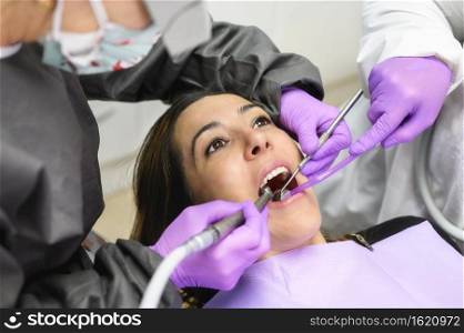 Young woman visit dentistry clinic for professional teeth treatment. Woman dentist bend over patient. Doctor holding instrument tool for oral examination. High quality photo. Young woman visit dentistry clinic for professional teeth treatment. Woman dentist bend over patient. Doctor holding instrument tool for oral examination. 