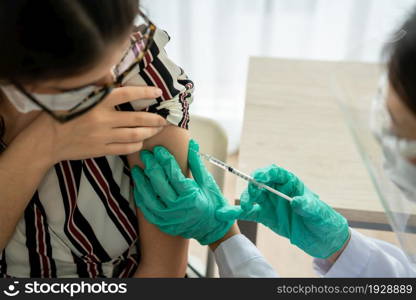 Young woman visits skillful doctor at hospital for vaccination . Covid 19 and coronavirus vaccination center service concept .. Young woman visits skillful doctor at hospital for vaccination