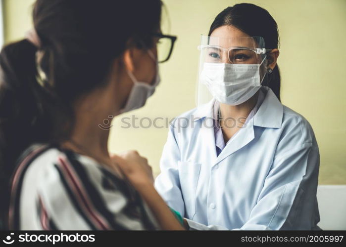 Young woman visits skillful doctor at hospital for vaccination . Covid 19 and coronavirus vaccination center service concept .. Young woman visits skillful doctor at hospital for vaccination