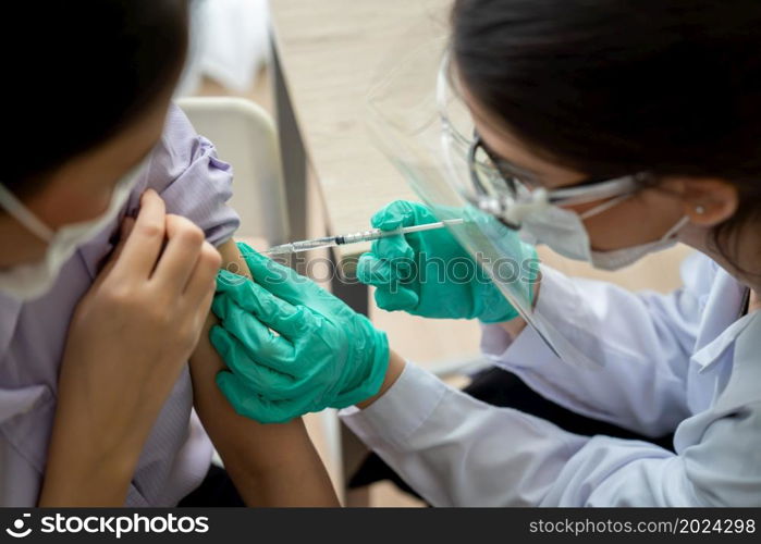 Young woman visits skillful doctor at hospital for vaccination . Covid 19 and coronavirus vaccination center service concept .. Young woman visits skillful doctor at hospital for vaccination