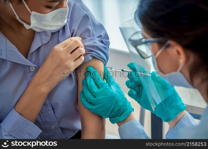 Young woman visits skillful doctor at hospital for vaccination . Covid 19 and coronavirus vaccination center service concept .. Young woman visits skillful doctor at hospital for vaccination