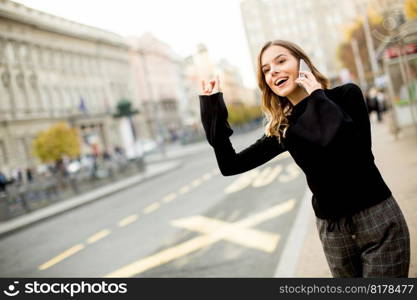 Young woman waiting for taxi or bus on the street in the city