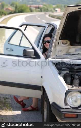 Young woman waiting in broke car