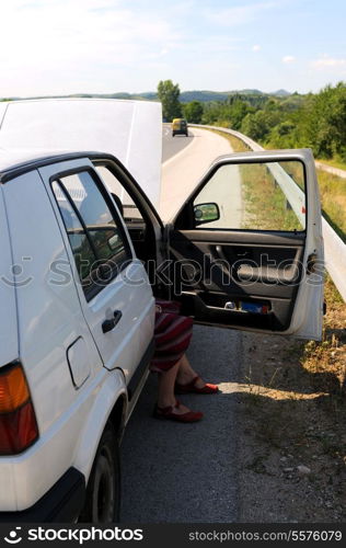 Young woman waiting in broke car