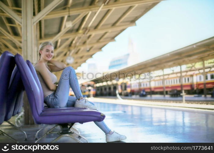 young woman waiting in vintage train, relaxed and carefree at the station platform in Bangkok, Thailand before catching a train. Travel photography. Lifestyle.