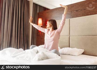 Young woman wake up in the morning, stretching in the bed, bedroom interoir on background. Young woman wake up in the morning, stretching