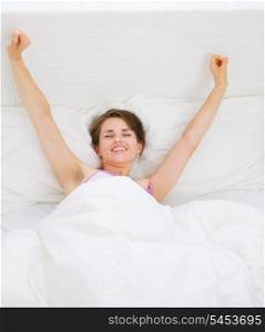 Young woman waking up and stretching