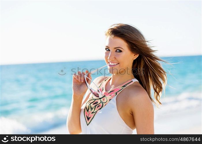 Young woman walking along the beach. Portrait of young pretty woman on summer day on sandy beach