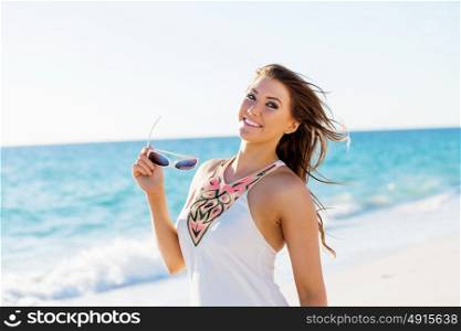 Young woman walking along the beach. Portrait of young pretty woman on summer day on sandy beach