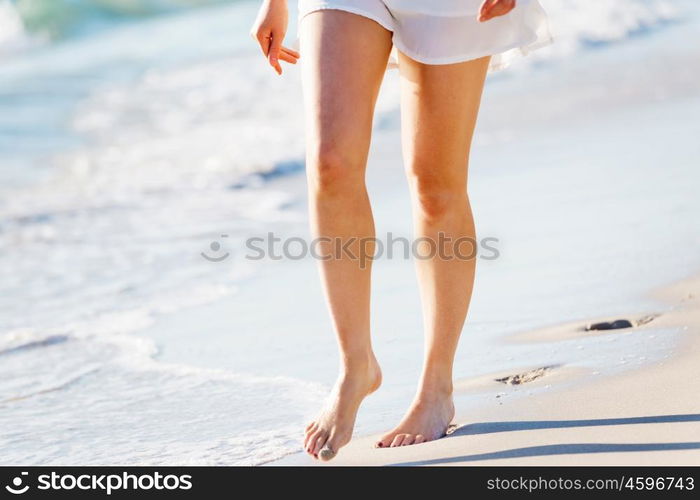 Young woman walking along the beach. Portrait of young pretty woman walking along sandy beach