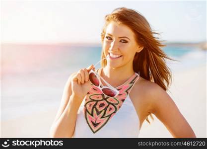 Young woman walking along the beach. Portrait of young pretty woman walking along sandy beach