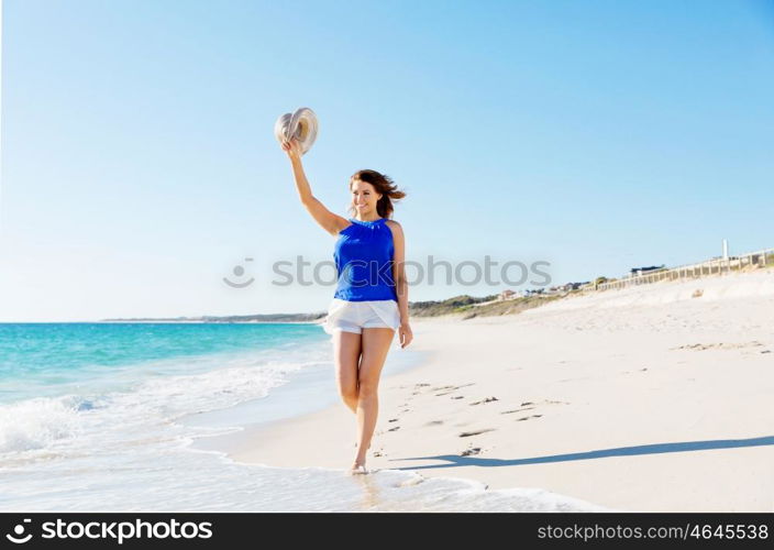 Young woman walking along the beach. Portrait of young pretty woman walking along sandy beach