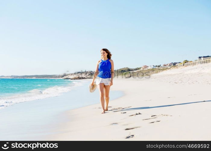 Young woman walking along the beach. Portrait of young pretty woman walking along sandy beach