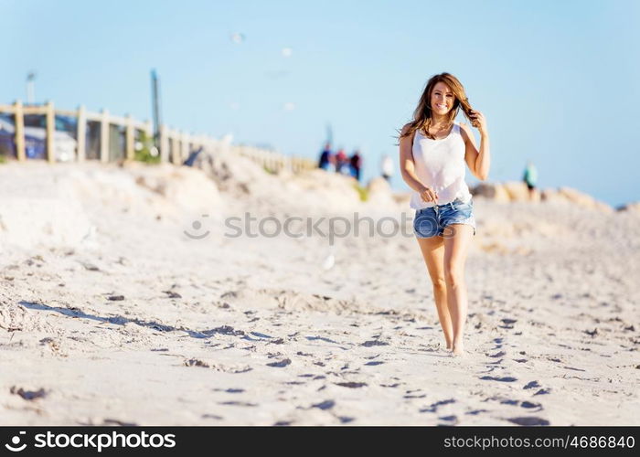 Young woman walking along the beach. Portrait of young pretty woman walking along sandy beach