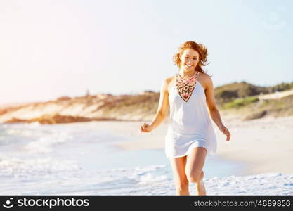 Young woman walking along the beach. Portrait of young pretty woman walking along sandy beach