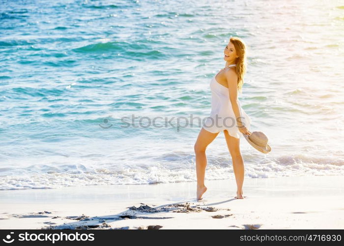 Young woman walking along the beach. Portrait of young pretty woman walking along sandy beach