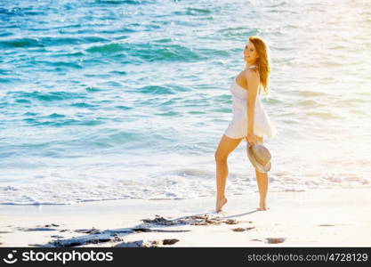 Young woman walking along the beach. Portrait of young pretty woman walking along sandy beach