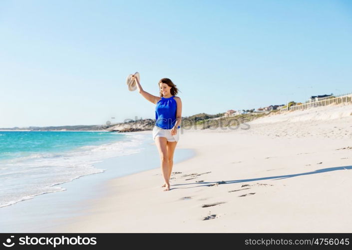 Young woman walking along the beach. Portrait of young pretty woman walking along sandy beach