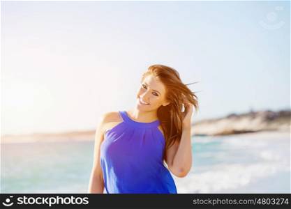 Young woman walking along the beach. Portrait of young pretty woman walking along sandy beach