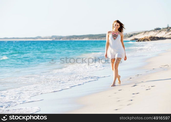 Young woman walking along the beach. Portrait of young pretty woman walking along sandy beach