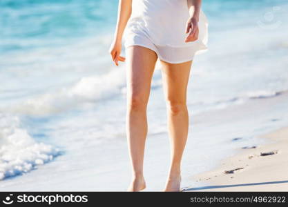 Young woman walking along the beach. Portrait of young pretty woman walking along sandy beach