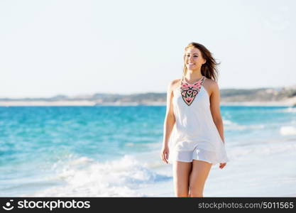 Young woman walking along the beach. Portrait of young pretty woman walking along sandy beach