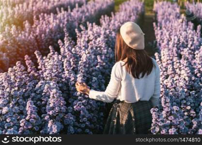 Young woman walking and enjoying in blooming flowers field in the morning