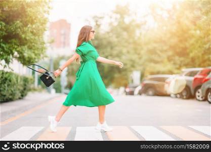 Young woman walking around the big city. Portrait of beautiful girl in green dress. Young woman in green dress in the city walks