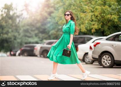 Young woman walking around the big city. Portrait of beautiful girl in the dress. Young woman in the city
