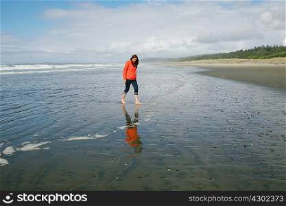 Young woman walking barefoot on beach, Long Beach, Vancouver Island, British Columbia, Canada