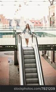 Young woman walking down the escalator at shopping mall
