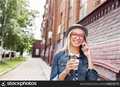 Young woman walking down the street. Young pretty girl tourist walking the street and talking on mobile phone