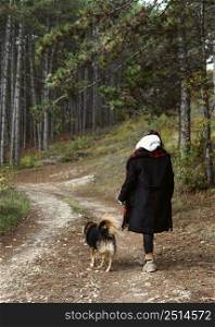 young woman walking forest with her dog