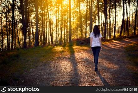 Young woman walking in the woods at sunset