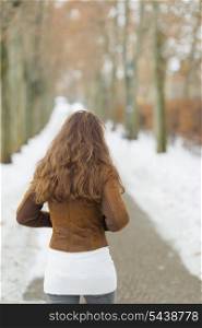 Young woman walking in winter park. rear view