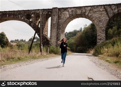 Young woman walking near old viaduct. Tourist girl in scenery countryside by the Historical abandoned railway arch bridge viaduct in Vorokhta, Ivano-Frankivsk Region, Ukraine.. Young woman walking near old viaduct. Tourist girl in scenery countryside by the Historical abandoned railway arch bridge viaduct in Vorokhta, Ivano-Frankivsk Region, Ukraine