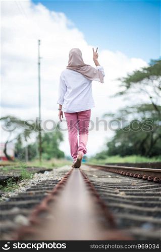 young woman walking on railroad tracks